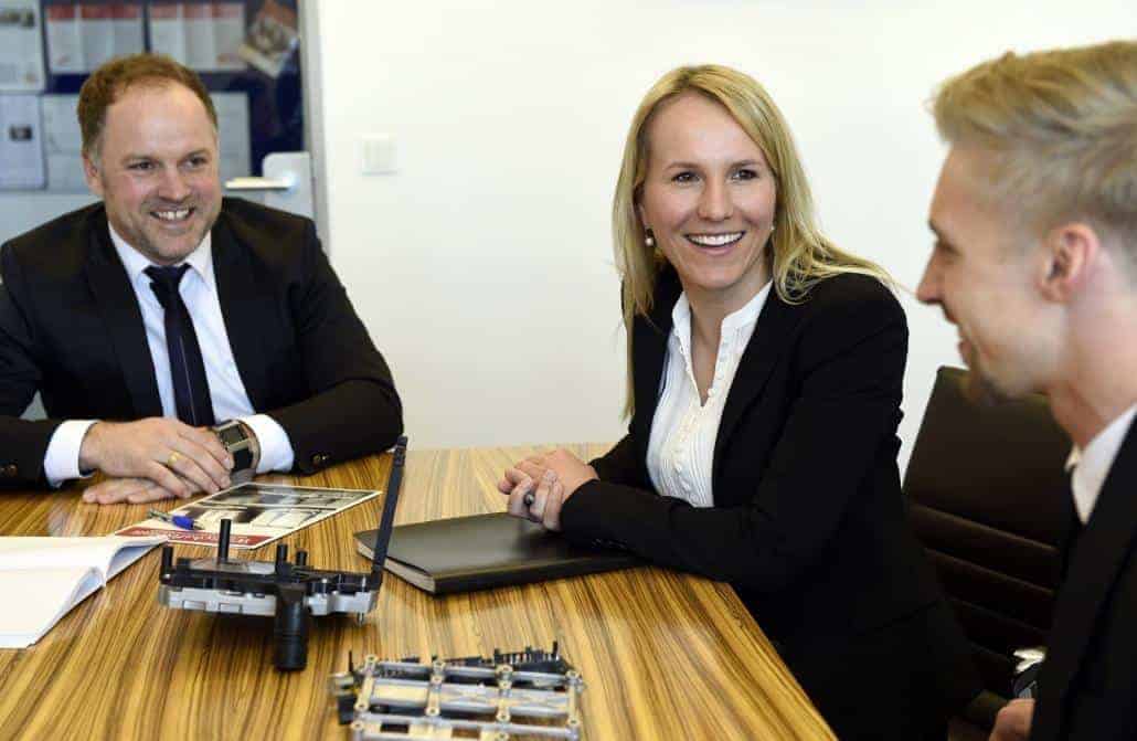 Neumüller Prokurist Christian Kaiser und Disponentin Katharina Fister sitzen an einem Tisch mit einem Bewerber.